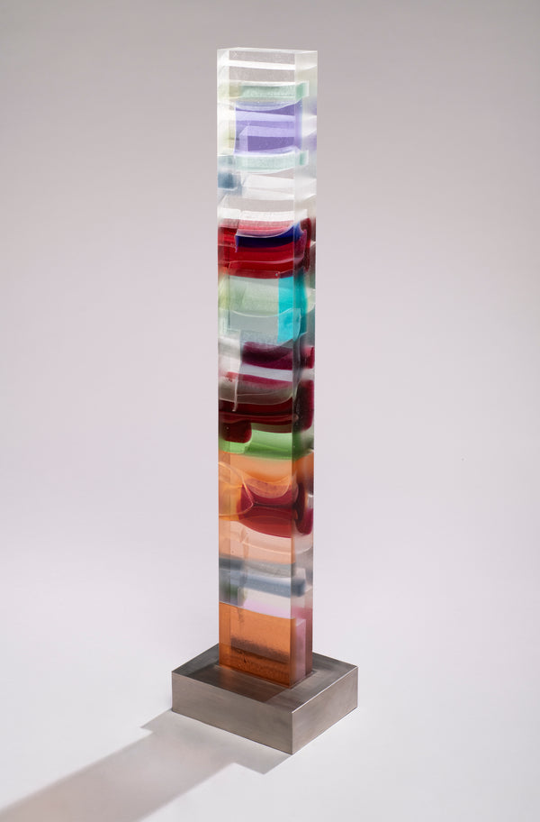 Wide glass column with wavy bands of violet, crimson, turquoise, green and amber on a brushed stainless steel base.