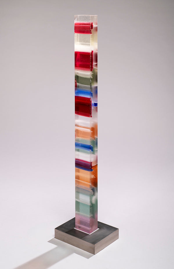 Clear glass column with horizontal bands of crimson, blue, orange, sage and plum rising from a wide brushed steel base.