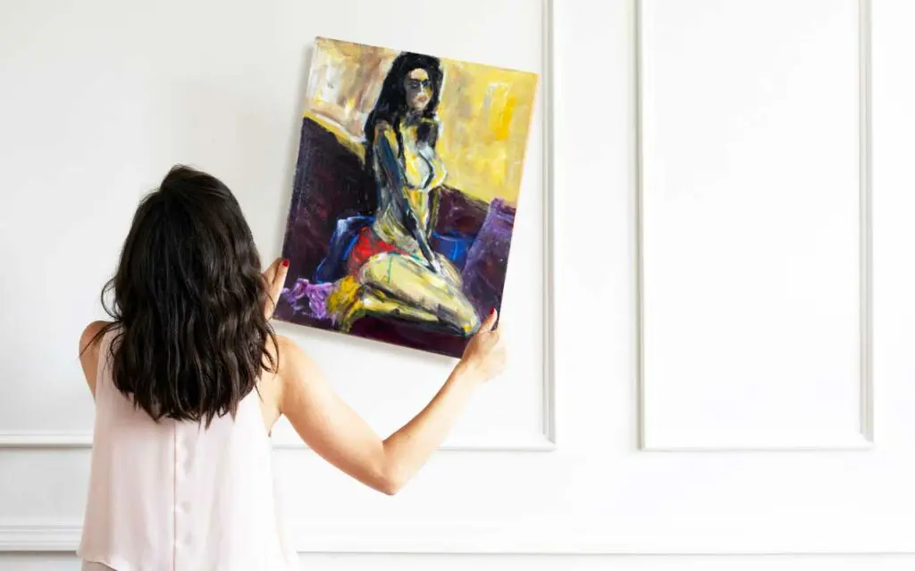 Woman hanging up ABOUT LAST NIGHT painting by Haleh Mashian after cleaning it