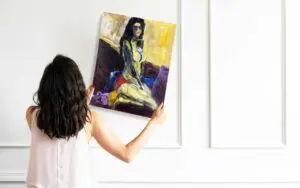 Woman hanging up ABOUT LAST NIGHT painting by Haleh Mashian after cleaning it