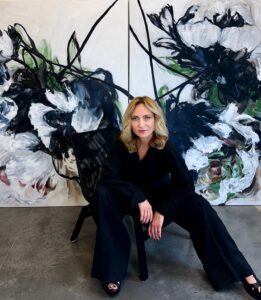 Ramona Stelzer artist photo in front of floral painting