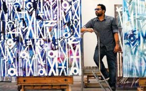 RETNA standing beside some of his works
